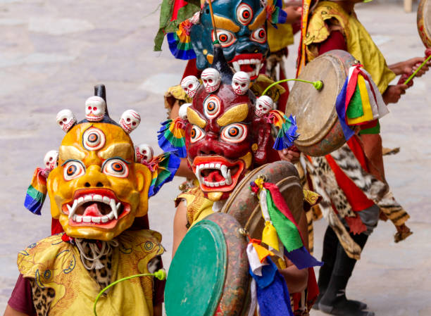 monjes no identificados con máscaras con tambores realiza una danza de misterio enmascarada religiosa y disfrazada del budismo tibetano durante el festival de danza cham en el monasterio de hemis - cham mask fotografías e imágenes de stock