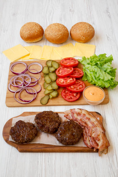 istock Burger ingredients on a white wooden table, side view. Closeup. 1149897902
