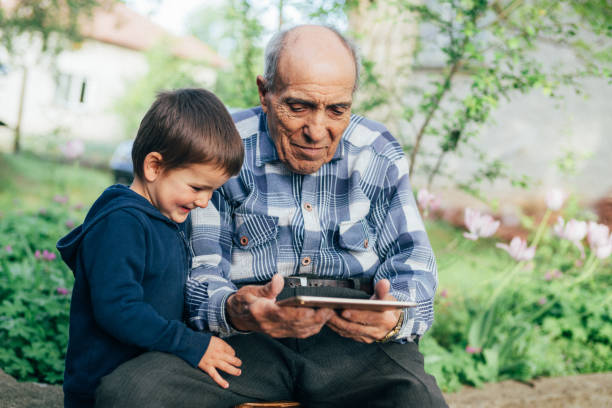 senior hombre viendo videos en la tableta con el nieto - great grandson fotografías e imágenes de stock