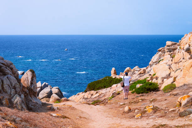 istock Man with camera at rocks of Capo Testa Mediterranean sea 1149909986
