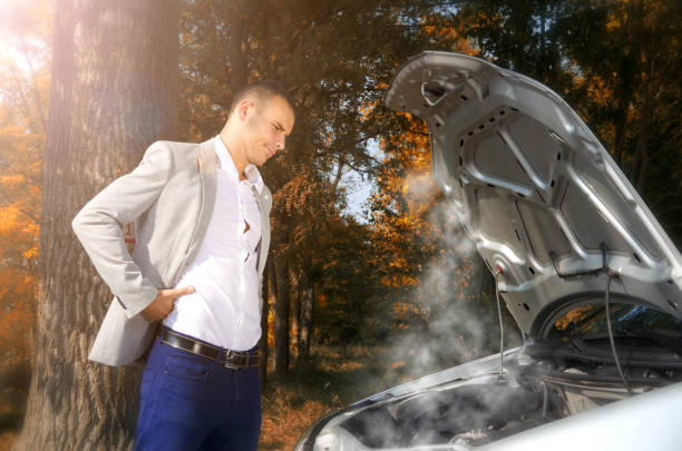 Caucasian businessman standing by the car with hood open trying to solve the problem. Smoke coming out of the engine. Car break down. overheated photos stock pictures, royalty-free photos & images