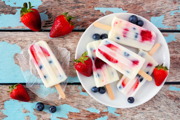 istock Healthy summer strawberry blueberry yogurt popsicles, top view table scene against blue wood 1149915607