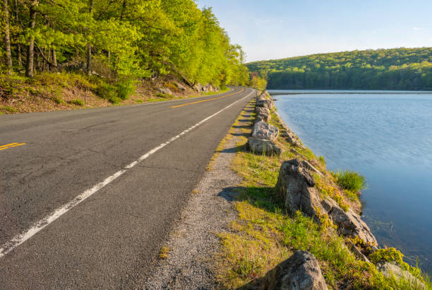 Peaceful morning view featuring road passing through the trees and lake at Seven lakes road, New York
