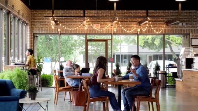 Mid adult Asian man enjoys coffee in coffee shop with his wife