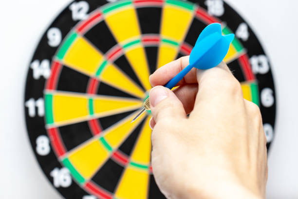 istock A hand holding a blue dart ready to throw it to a dartboard target, strategy and skill in business concept 1149933641