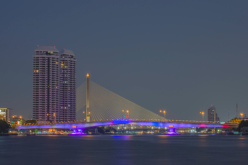 The beauty of colorful lights on Pinklao bridge and cars driving at Night on Chao Phraya River, Bangkok in Thailand.