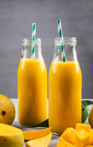 istock Close Up Of Mango Smoothie In A Bottle With Straw And Mango Slices On A Table 1150000147
