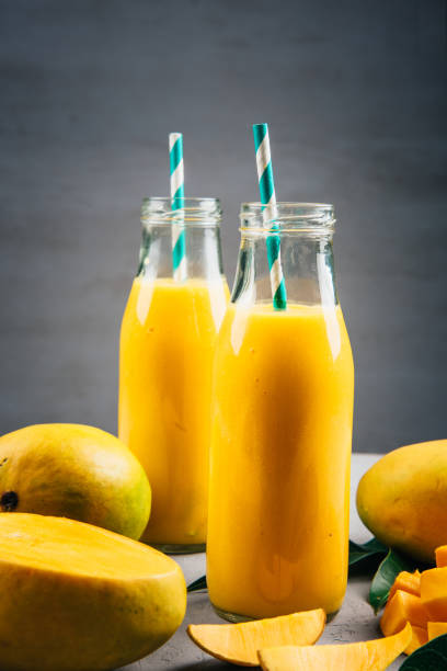 istock Close Up Of Mango Smoothie In A Bottle With Straw And Mango Slices 1150000155
