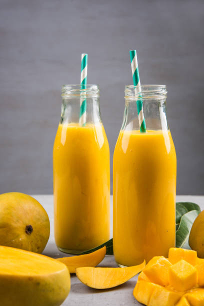 istock Close Up Of Mango Smoothie In A Bottle With Straw And Mango Slices On A Table 1150000158