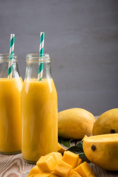 istock Close Up Of Mango Smoothie In A Bottle With Straw And Mango Slices 1150000159