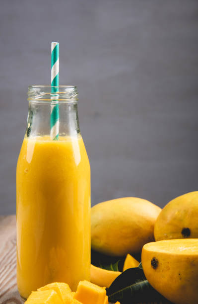 istock Close Up Of Mango Smoothie In A Bottle With Straw And Mango Slices 1150000162
