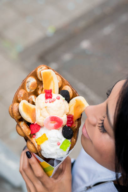 A tall stack of empty ice cream cones is displayed at a dessert stand. Sunshine illuminates the scene, creating a cheerful atmosphere perfect for enjoying treats