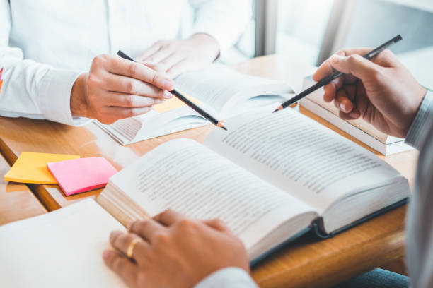 istock High school or college students studying and reading together in library 1150017914