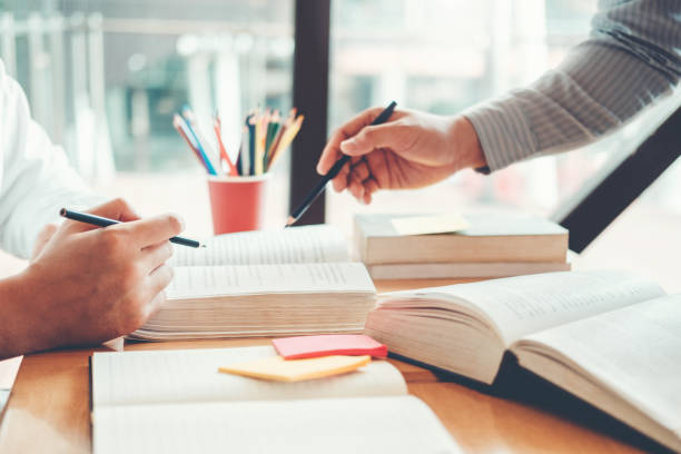istock High school or college students studying and reading together in library 1150017986