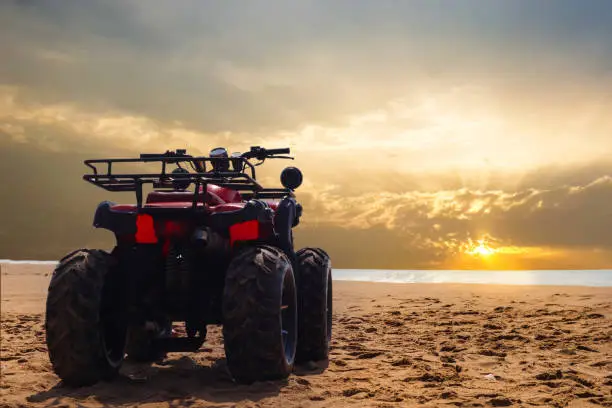 four wheeler dirt bike on sand of sea beach during sunset