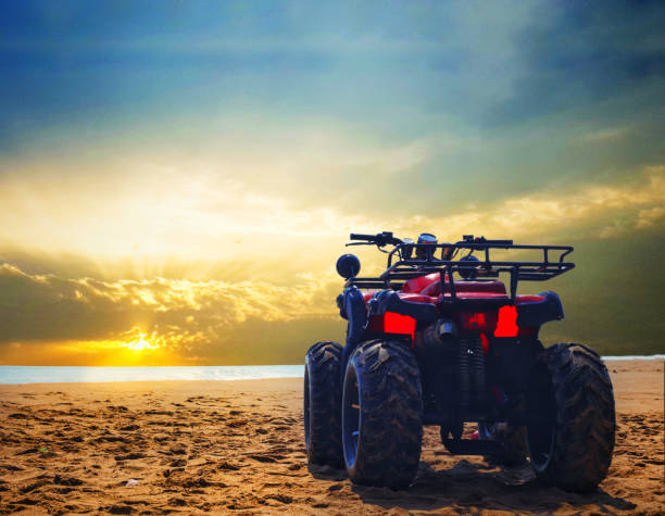 four wheeler dirt bike on sand of sea beach during sunrise with dramatic colourful sky four wheeler dirt bike on sand of sea beach during sunrise with dramatic colourful sky motorcycle 4 wheels stock pictures, royalty-free photos & images