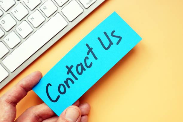 istock Hand holds sign Contact us and keyboard. 1150025082
