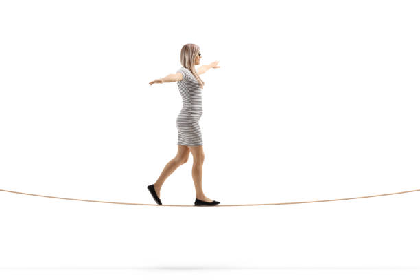 Young blond woman walking on a rope with arms spread Full length profile shot of a young blond woman walking on a rope with arms spread isolated on white background tightrope stock pictures, royalty-free photos & images