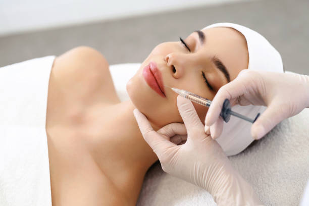 istock Lips injection. Syringe with filler for lips contouring or augmentation. Model lying at coach in beautician office, top point of view. Cosmetological clinic. Healthcare, cosmetology concept. 1150026721