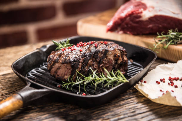 steak de boeuf grillé dans la casserole de gril avec le romarin d’herbes sur la table en bois - eye fillet photos et images de collection