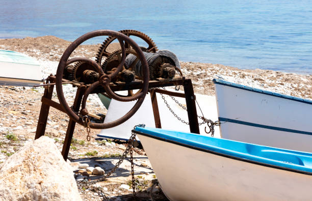 mechanism to drag the boats to the shore in the beach, it is corroded but in use, there are some white boats