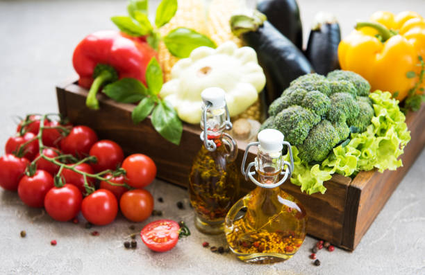 different raw vegetables and olive oil on a concrete background