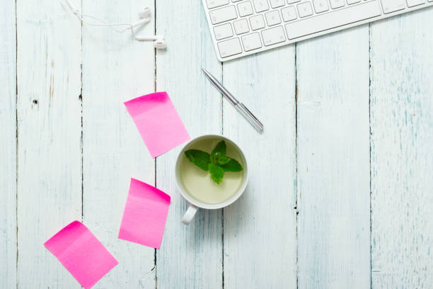Mint tea, pink post its on office table work place with cup of mint tea, pink post its and pen, directly above white shabby chic desk stock pictures, royalty-free photos & images