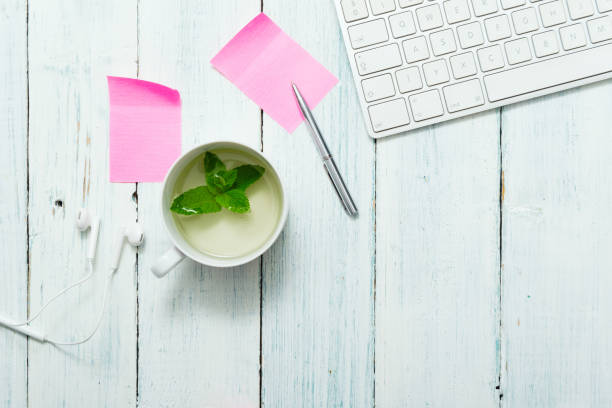 Mint tea, pink post its on office table work place with cup of mint tea, pink post its and pen, directly above white shabby chic desk stock pictures, royalty-free photos & images