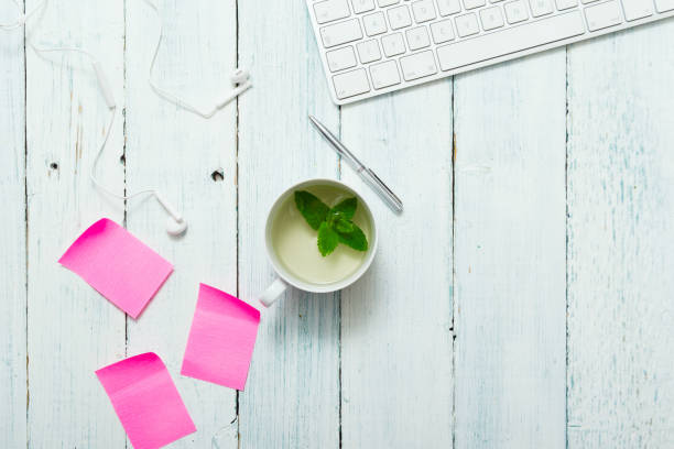 Mint tea, pink post its on office table work place with cup of mint tea, pink post its and pen, directly above white shabby chic desk stock pictures, royalty-free photos & images