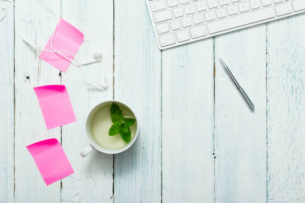 Mint tea, pink post its on office table work place with cup of mint tea, pink post its and pen, directly above white shabby chic desk stock pictures, royalty-free photos & images