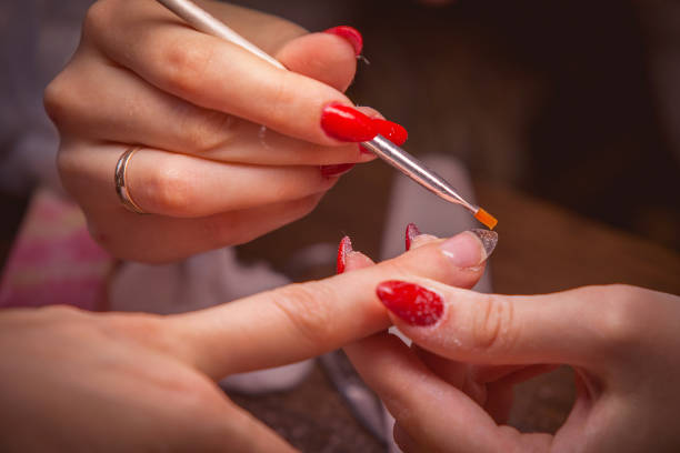 maniküren. meister machen nagelverlängerung: zeichnung des weißen gels auf der freien kante des nagels - work tool hand tool home improvement nail stock-fotos und bilder