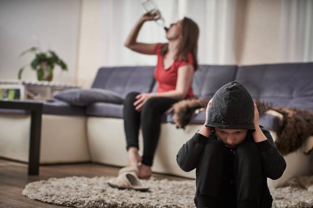 madre alcol bevande alcoliche da una bottiglia. il bambino è chiuso dal problema dell'ubriachezza in famiglia. un bambino indifeso è chiuso per disperazione. difficoltà in famiglia.indifferenza - alcohol alcoholism addiction drinking foto e immagini stock