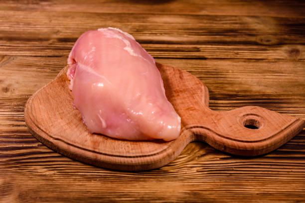 istock Cutting board with raw chicken fillet on wooden table 1150047033