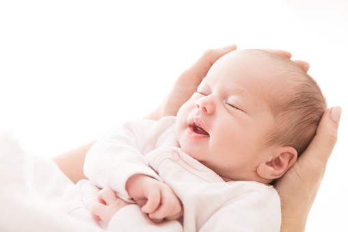Sueño de bebé recién nacido en manos de la madre, nueva chica nacida sonriendo y durmiendo photo