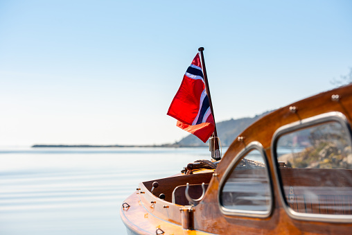 The norwegian flag in the aft mast of a wooden boat.