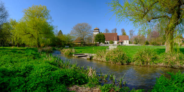 spring sunshine on st andrew's church in meonstoke in the south downs national park, hampshire, uk - grass church flood landscape imagens e fotografias de stock