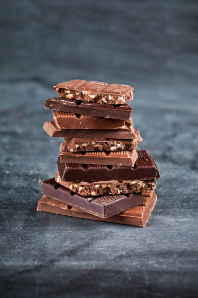 istock Chocolate bar pieces stack on black background. Sweet food photo concept. 1150058220