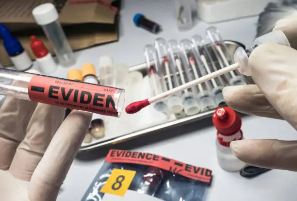 Photo of Police expert extracts traces of blood in a swab for analysis in the laboratory scientist, conceptual image