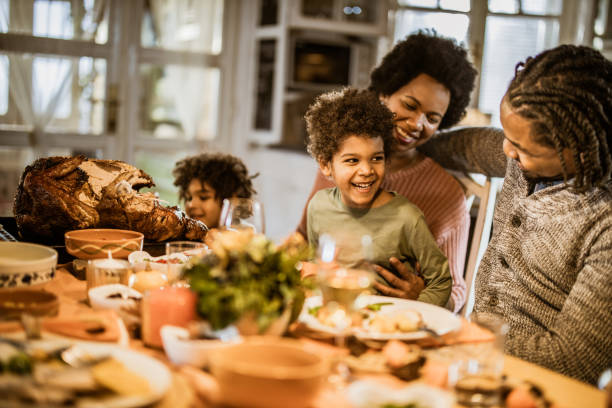 istock Happy black boy talking to his parents during Thanksgiving dinner at dining table. 1150062173