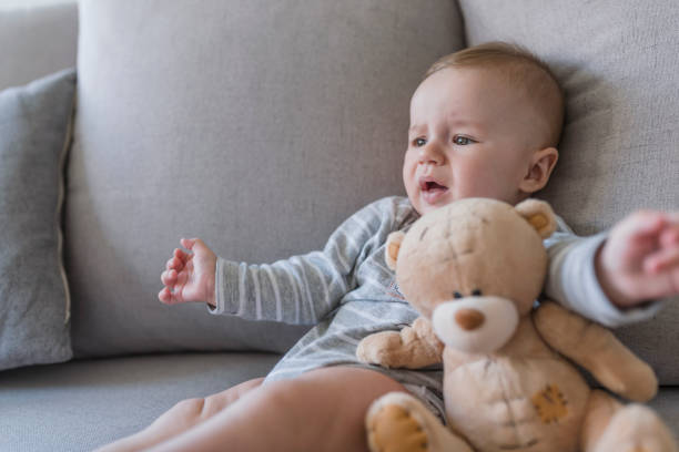 bébé pleurant au lit avec un ours en peluche. - screaming little boys child human teeth photos et images de collection