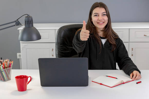 Cheerful young freelancers are smiling, looking at laptop in nice modern work station at office, in casual smart wears