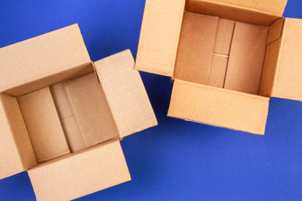 duas caixas de cartão abertas vazias no fundo azul - distribution warehouse sending gift delivering - fotografias e filmes do acervo