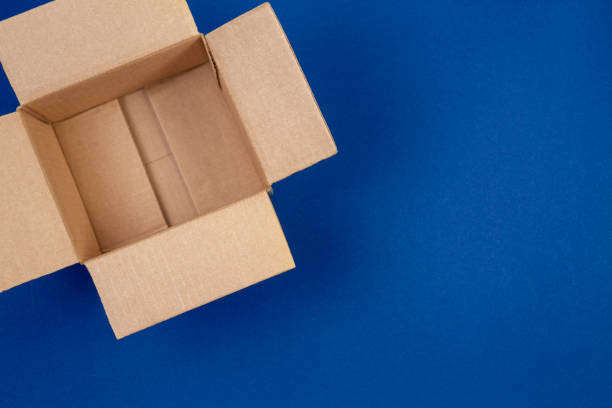 open empty cardboard boxes on blue background - cardboard box imagens e fotografias de stock