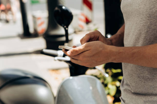 A guy or a tourist activates or rents an electric scooter using a mobile application on a cell phone.