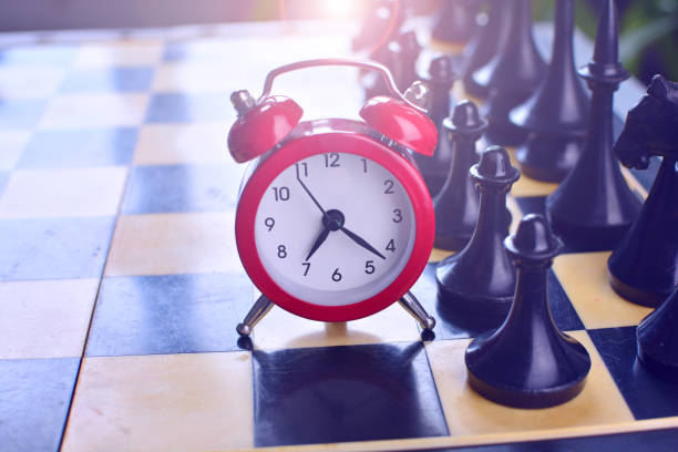 istock Red alarm clock near the black chessmen 1150071177