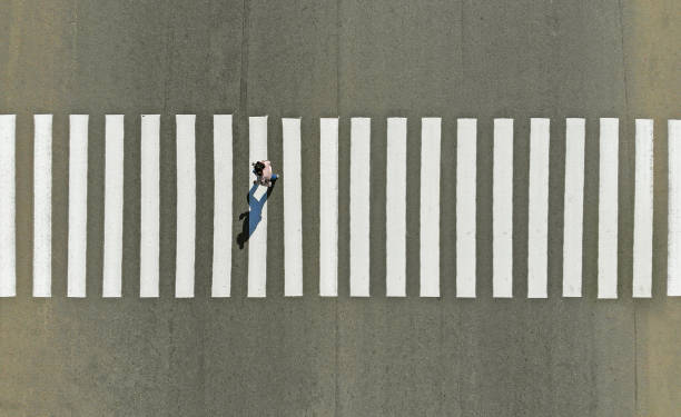 istock One pedestrian crossing zebra crosswalk, aerial, top view 1150072468