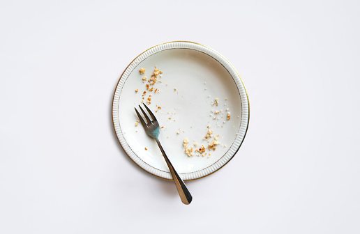 Empty plate with crumbs after eating on a white background.