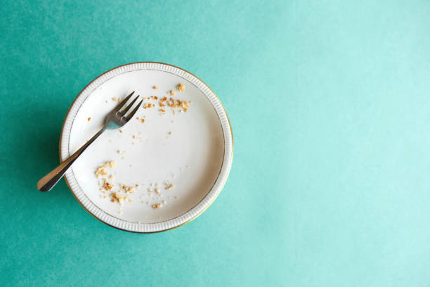 緑の背景に食べた後、パンくずと空のプレート。休日やお祝いの終わりの概念。テキストのための近くの場所 - plate crumb dirty fork ストックフォトと画像