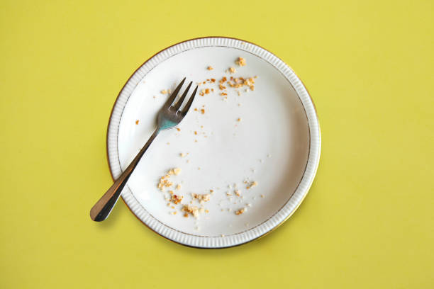 Empty plate with crumbs after eating on a yellow background. The concept of the end of the holiday or celebration stock photo