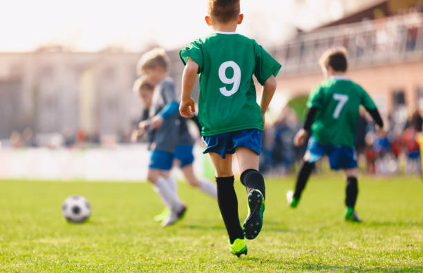 garçons jouant dans un match de football - niveau junior photos et images de collection